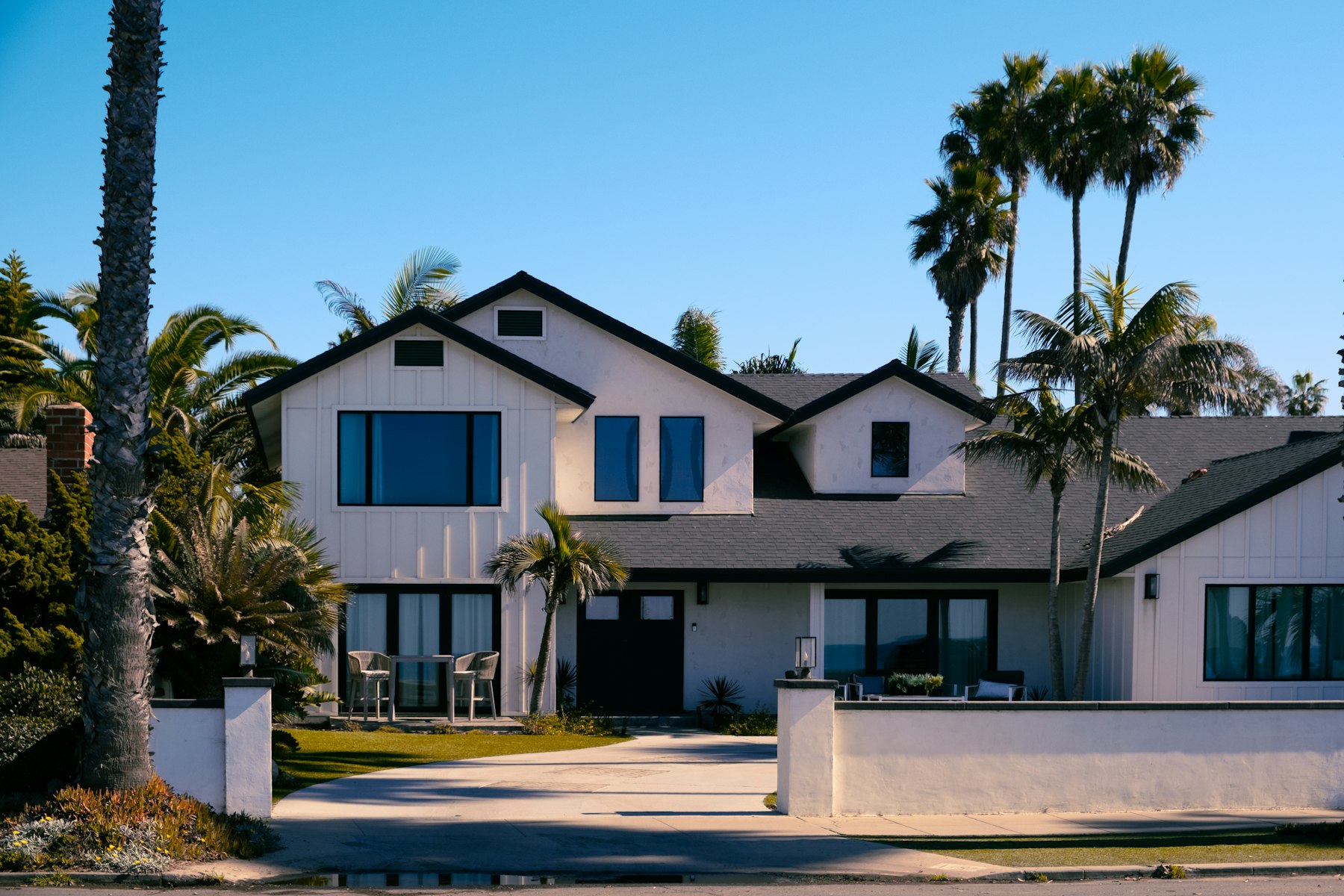 A white two-story house with palm trees in Southern California